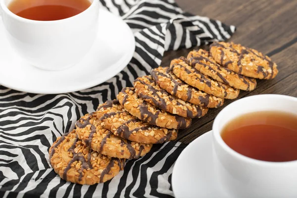 Tahta bir masaya yerleştirilmiş beyaz fincanlı çok tahıllı kurabiyeler. Yüksek kalite fotoğraf