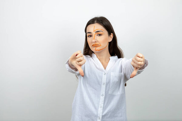 Image of young woman with painted face showing thumbs down . High quality photo