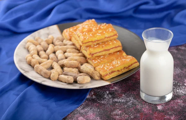 Glass pitcher of milk with healthy peanuts in shell and crackers . High quality photo