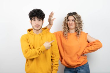 Beyaz duvarın üzerinde duran genç ve çekici bir çiftin portresi. Yüksek kalite fotoğraf