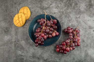 Kırmızı olgun üzümler ve mermer yüzeyde dilimlenmiş mango tabakası. Yüksek kalite fotoğraf