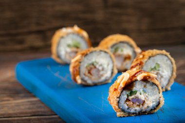 Tahta bir kesme tahtasına yerleştirilmiş taze lezzetli suşi dürümleri. Yüksek kalite fotoğraf