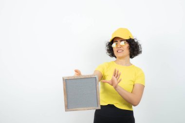 Beyaz arka planda poz veren pankartlı genç kadın. 