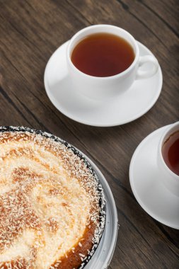 Lezzetli hindistan cevizli kek ve ahşap arka planda bir fincan siyah çay. Yüksek kalite fotoğraf