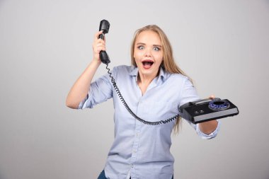 Kablolu telefondan konuşan güzel bir bayanın fotoğrafı. Gri bir arka plan. Yüksek kalite fotoğraf