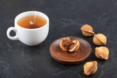 Siyah arka planda bir fincan çayla ceviz şeklinde lezzetli kurabiyeler. Yüksek kalite fotoğraf