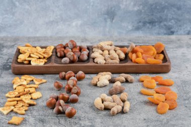 Fındık dolu ahşap tabak, kraker ve mermer yüzeyde kurutulmuş kayısılar. Yüksek kalite fotoğraf