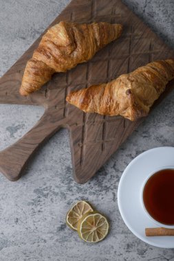 Tahta kesme tahtası, taze kruvasan ve bir fincan sıcak çay. Yüksek kalite fotoğraf