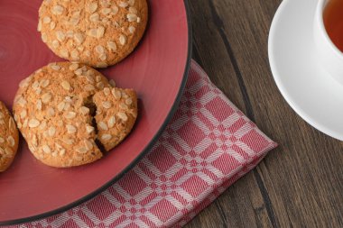 Kırmızı tabak ve yulaflı kurabiyeler ahşap masada bir fincan çay. Yüksek kalite fotoğraf