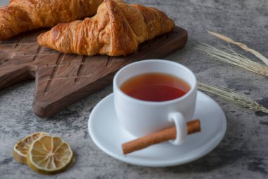 Tahta kesme tahtası, taze kruvasan ve bir fincan sıcak çay. Yüksek kalite fotoğraf