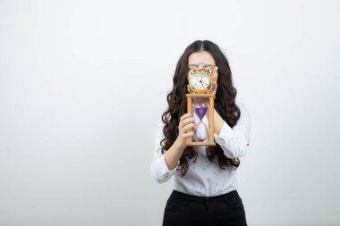 Kum saati ve çalar saat tutan uzun saçlı genç kadının portresi. Yüksek kalite fotoğraf