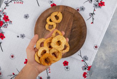 Erkek eli mermer yüzeyde kurumuş elma halkaları tutuyor. Yüksek kalite fotoğraf