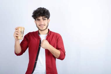 Beyaz duvarda mola vermek için elinde kahve tutan esmer adamın fotoğrafı. Yüksek kalite fotoğraf