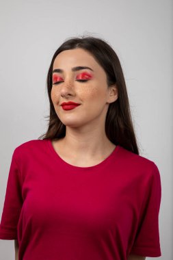 Beyaz bir duvarın üzerinde duran ve poz veren genç bir kadın resmi. Yüksek kalite fotoğraf