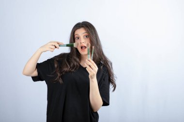 Beyaz arka planda fırçayla allık süren genç ve güzel bir model resmi. Yüksek kalite fotoğraf