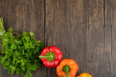 Ahşap arka planda renkli dolmalık biber ve yeşil maydanoz yaprakları. Yüksek kalite fotoğraf