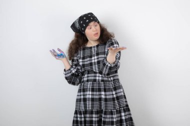 Down sendromlu genç bir kız beyaz arka planda elindeki renklere bakıyor. Yüksek kalite fotoğraf