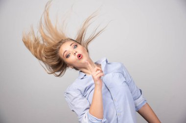 Uçan saçlı, gri arka planda kameraya bakan güzel sarışın kızın portresi. Yüksek kalite fotoğraf