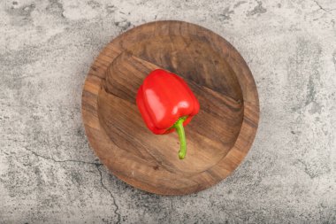 Single fresh red bell pepper on wooden plate. High quality photo