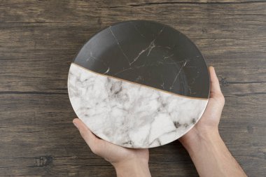 Ahşap bir masada boş bir tabak tutan erkek elleri. Yüksek kalite fotoğraf