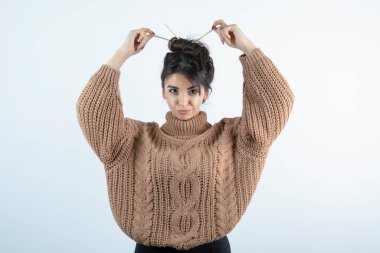 Saçlarını kalemle ören örgü elbiseli güzel bir kadının portresi. Yüksek kalite fotoğraf