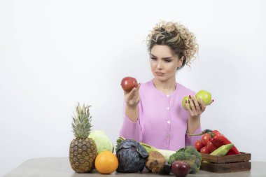 Güzel ev hanımının elinde taze elmalarla masada oturduğu bir fotoğraf. Yüksek kalite fotoğraf