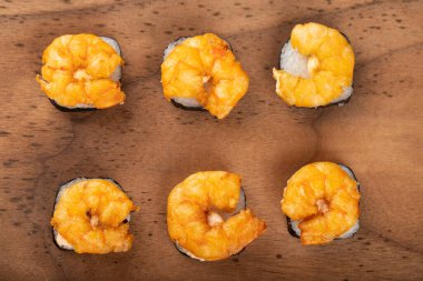 Tahta kesme tahtasına yerleştirilmiş karidesli taze lezzetli suşi ruloları. Yüksek kalite fotoğraf