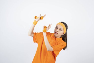 Turuncu tişörtlü, dambılı genç bir sporcunun resmi. Yüksek kalite fotoğraf