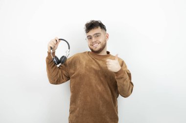 Siyah kulaklık takan ve onaylayan genç bir erkek manken resmi. Yüksek kalite fotoğraf