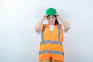 Beyaz duvarda yeşil kaskını takan genç bir kadın inşaat işçisi. Yüksek kalite fotoğraf