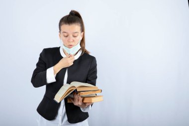 Beyaz duvarda kitap okuyan genç bir kız öğrencinin portresi. Yüksek kalite fotoğraf