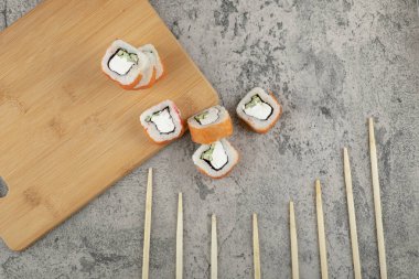 Taş zeminde taze somonla süslenmiş lezzetli suşi ruloları. Yüksek kalite fotoğraf