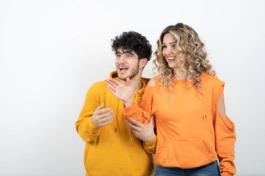 Beyaz duvarın üzerinde duran genç ve çekici bir çiftin portresi. Yüksek kalite fotoğraf