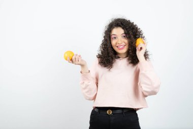 Portakal tutan pembe kazaklı genç kıvırcık kadın portresi. Yüksek kalite fotoğraf