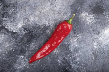 Single organic chili pepper placed on marble surface. High quality photo