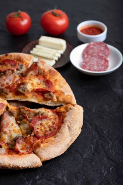 Siyah masaya konmuş kırmızı taze domatesli ve salamlı sıcak pizza. Yüksek kalite fotoğraf