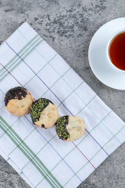 Chocolate glazed cookies and cup of aroma tea on marble surface. High quality photo
