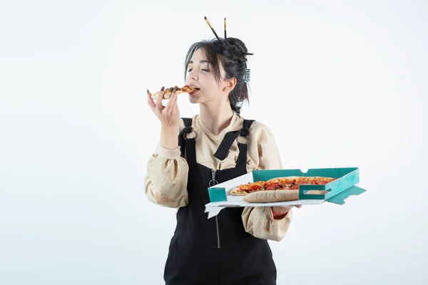 stock image Young woman holding a box with delicious pizza and eating a slice of pizza . High quality photo