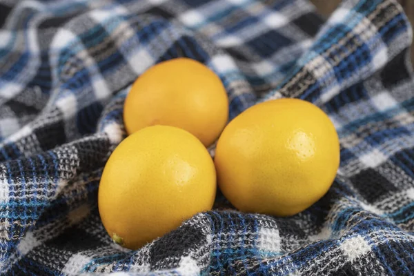 three organic yellow lemon on cotton table-cloth. High quality photo