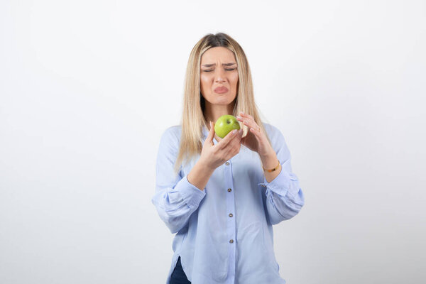 Portrait photo of a pretty attractive woman model standing and holding a green fresh apple . High quality photo