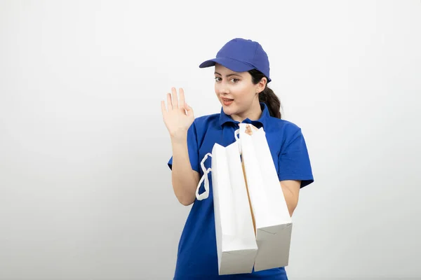 Mensajera Sonriente Traje Azul Con Bolsos Blancos Agitando Mano Foto —  Fotos de Stock