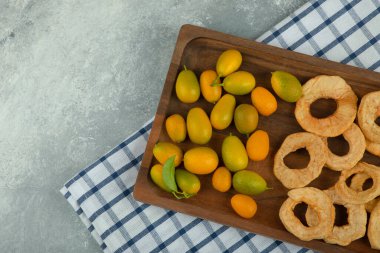 Mermer yüzeyde kurumuş elma halkaları ve kumkatlardan oluşan ahşap bir tabak. Yüksek kalite fotoğraf