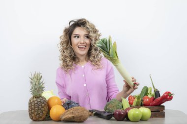 Masada oturan pembe tişörtlü, aç bakışlı sarışın kadının fotoğrafı. Yüksek kalite fotoğraf