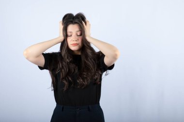 Esmer kızın beyaz arka planda saçlarını tutarken çekilmiş bir fotoğrafı. Yüksek kalite fotoğraf