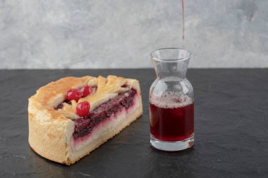 Dilimlenmiş lezzetli peynirli kek, böğürtlenli ve bir bardak taze meyve suyu, siyah arka planda. Yüksek kalite fotoğraf