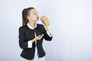 Beyaz arka planda bir fincan kahve içen genç bir kadının fotoğrafı. Yüksek kalite fotoğraf