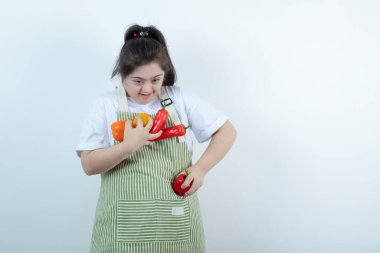 Kareli önlüğün içinde duran ve cebine sebze koyan genç ve güzel bir kız. Yüksek kalite fotoğraf