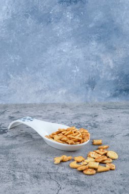 Beyaz seramik kaşık mermer zemin üzerinde tuzlanmış krakerlerle dolu. Yüksek kalite fotoğraf