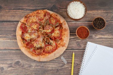 Lezzetli salamlı pizza, bir kase un ve ahşap masada boş kağıt. Yüksek kalite fotoğraf