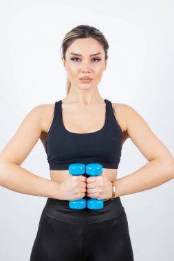 Siyah elbiseli sarışın kadın ayakta duruyor ve dambıllarıyla egzersiz yapıyor. Yüksek kalite fotoğraf